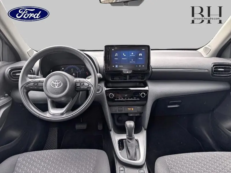 Vue intérieure avant de la Toyota Yaris Cross 116h Dynamic 2024, tableau de bord avec écran tactile et volant multifonction.