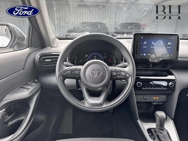 Vue intérieure frontale du tableau de bord et volant cuir multifonction noir de la Toyota Yaris Cross blanche 2024.