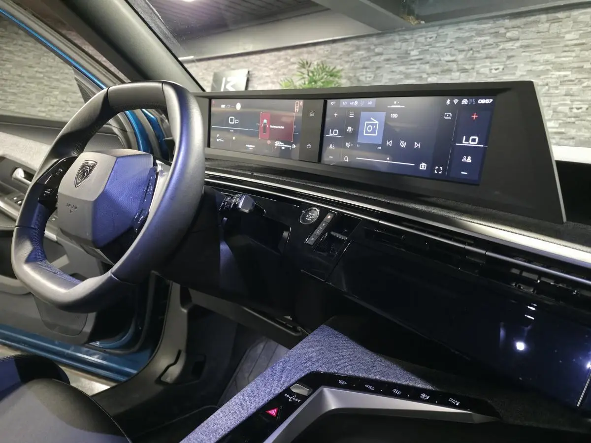Vue intérieure côté conducteur du Peugeot 5008 bleu 2025, avec tableau de bord numérique panoramique et volant compact cuir.