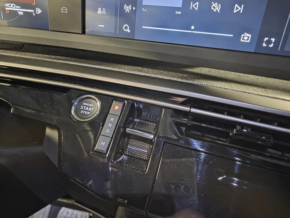 Détail de la console centrale noire laquée avec bouton start/stop et commandes de boîte automatique du Peugeot 5008 hybride 2025.