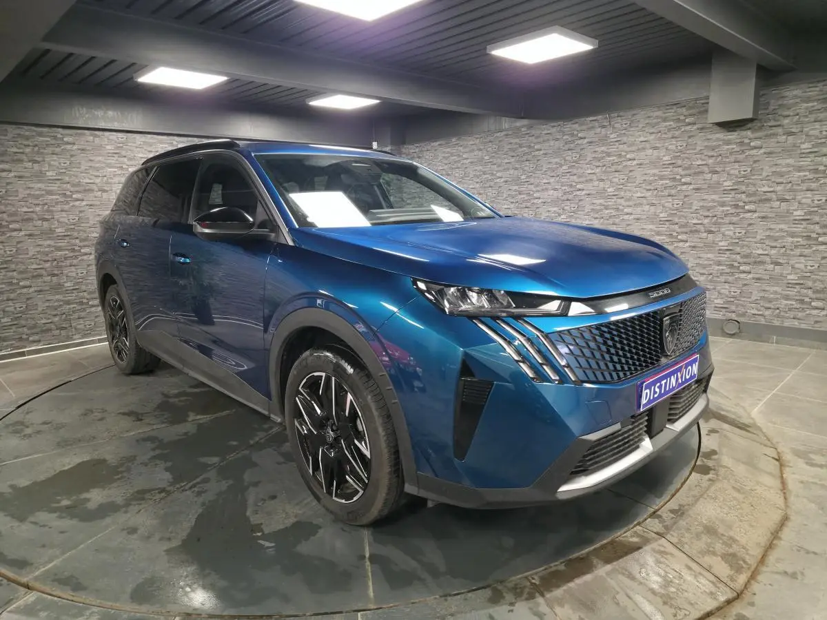 Peugeot 5008 bleu métallisé en 3/4 avant droit, avec calandre noire et jantes alliage 19'' diamantées.