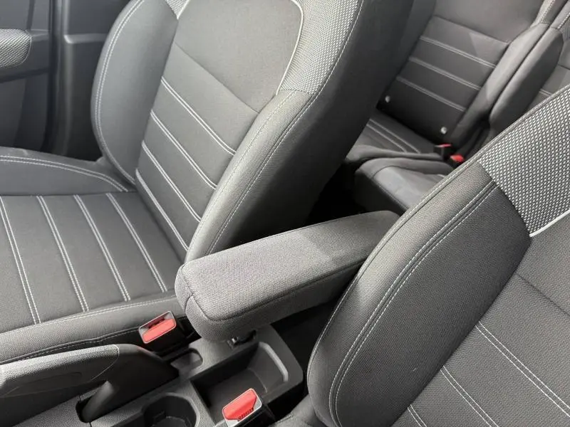 Gros plan sur les sièges avant gris foncé du Dacia Jogger 2025, mettant en valeur l'accoudoir central et les surpiqûres blanches.