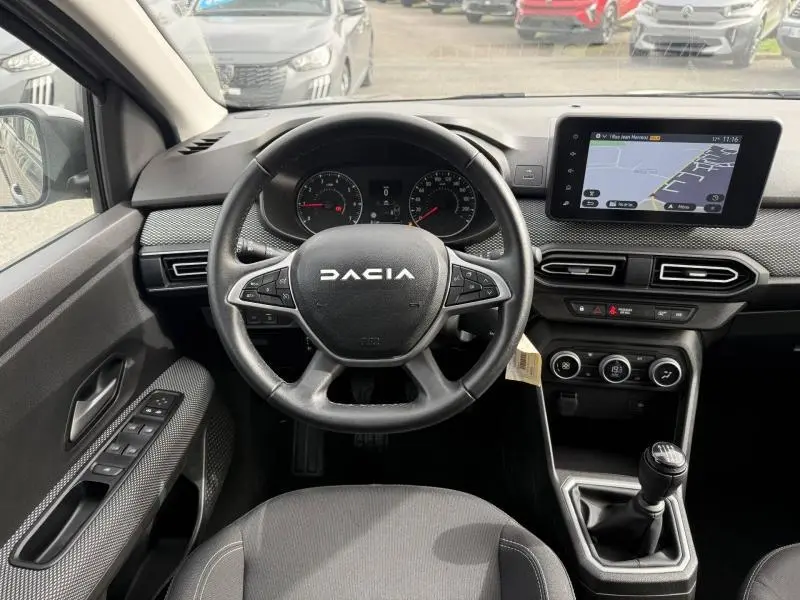 Vue intérieure frontale du poste de conduite du Dacia Jogger 2025, volant multifonction et écran tactile avec navigation.