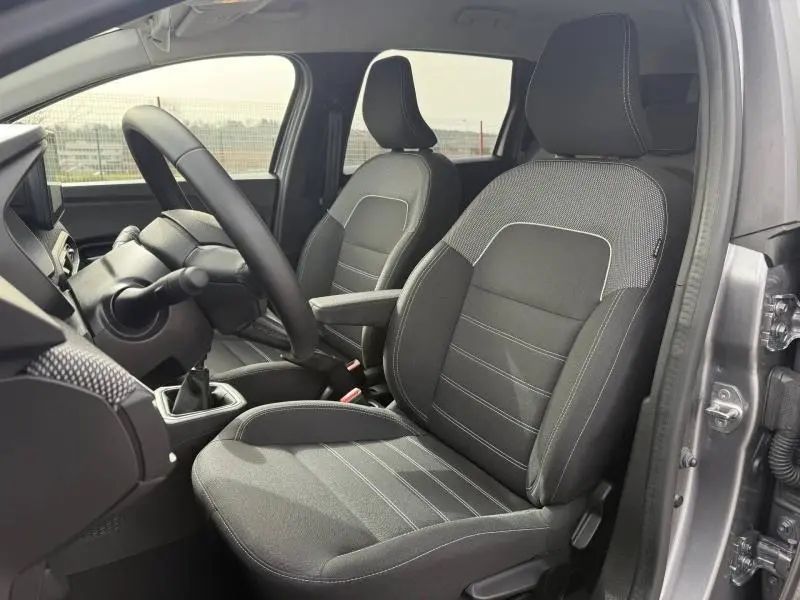 Vue intérieure côté conducteur du Dacia Jogger 2025 gris schiste, sièges tissu noirs avec surpiqûres claires et boîte manuelle.