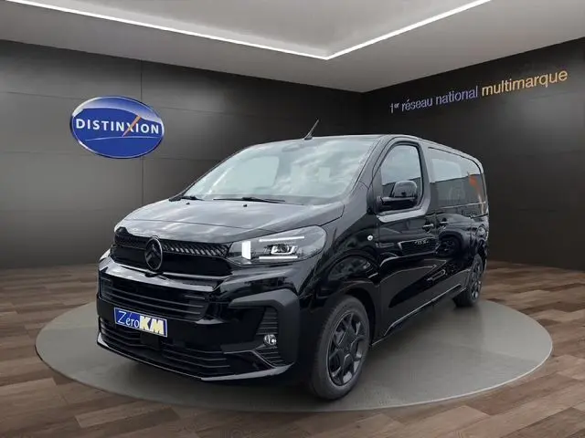 Vue 3/4 avant d'un Citroën Jumpy noir 2025 avec phares LED et jantes noires, présenté en intérieur showroom.