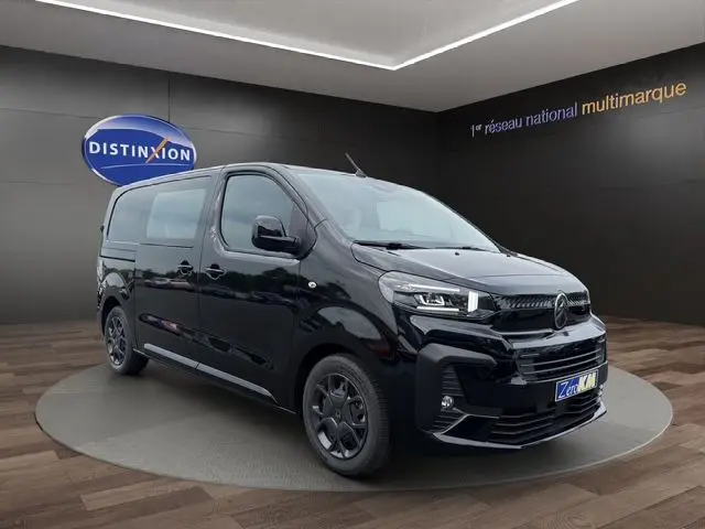 Vue 3/4 avant droite du Citroën Jumpy noir 2025 avec phares LED et jantes noires sur fond intérieur showroom.