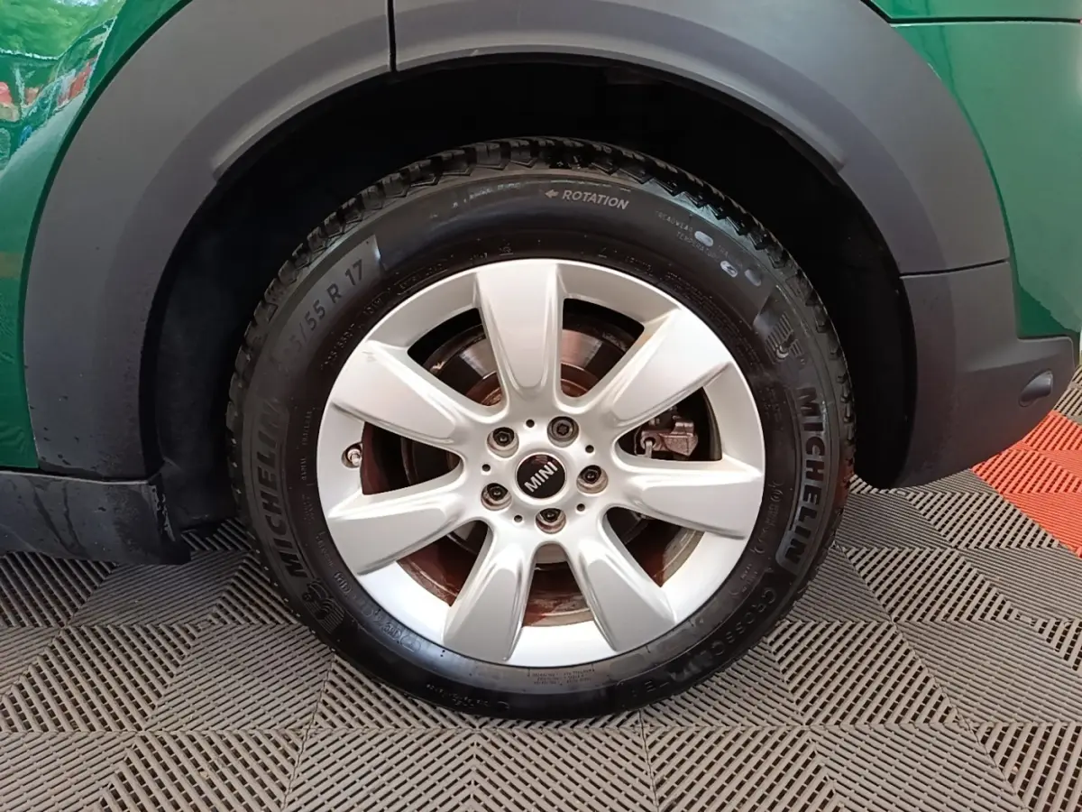 Gros plan sur la roue avant droite d'une MINI Countryman hybride, jante argentée et carrosserie verte visible.