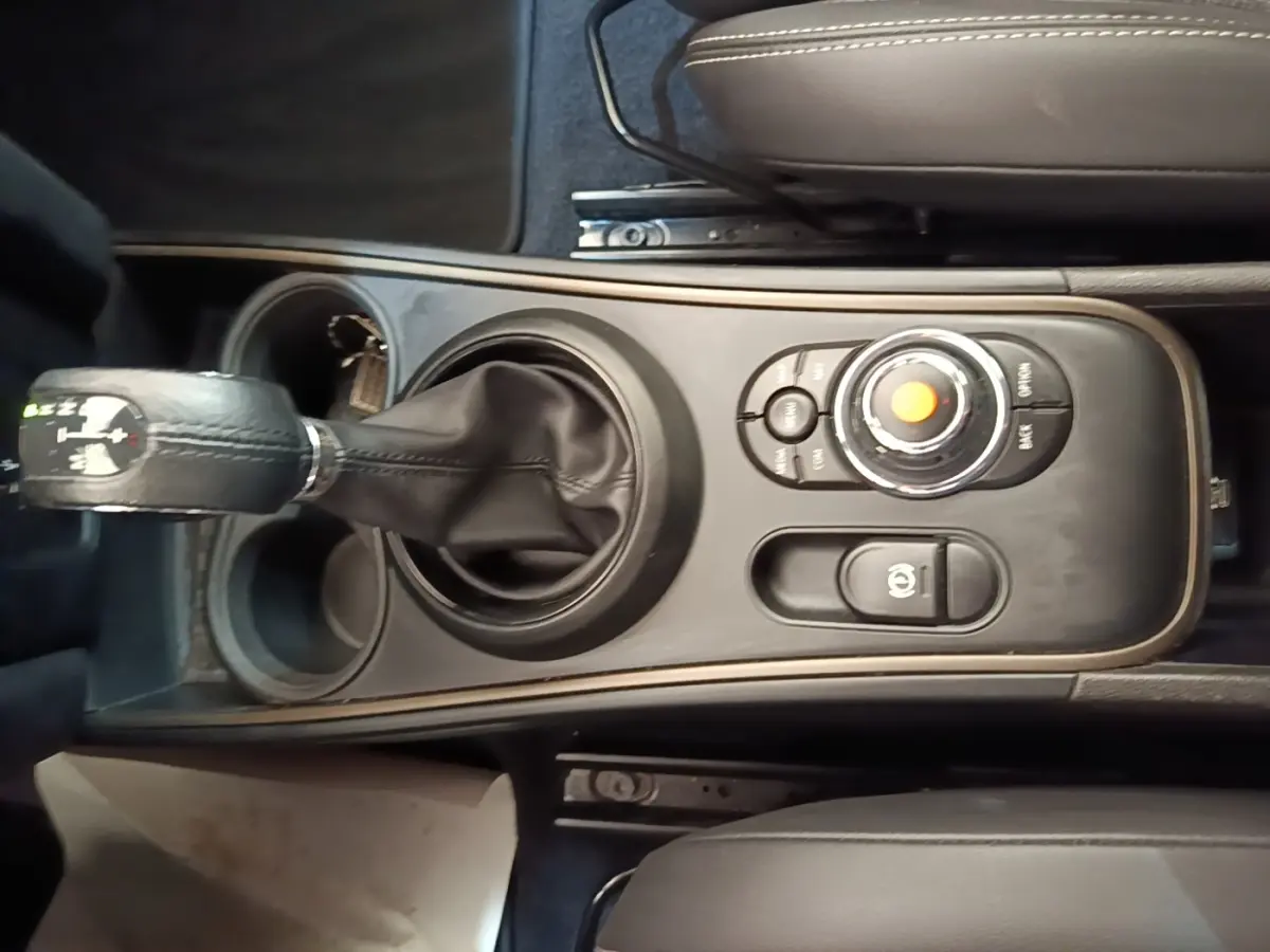 Vue plongeante sur la console centrale noire du MINI Countryman gris clair, avec levier de vitesses et molette de commande.