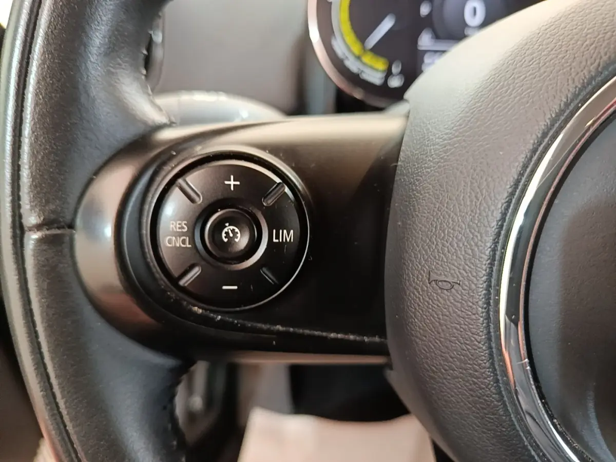 Gros plan sur le volant noir du MINI Countryman hybride, avec commandes de régulateur de vitesse au centre à gauche.