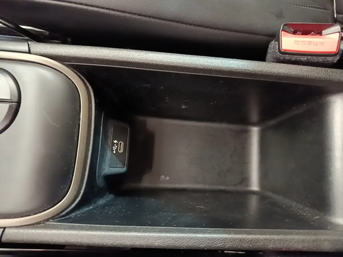 Vue rapprochée de la console centrale noire du MINI Countryman Cooper SE avec port USB-C et bouton de frein à main rouge.