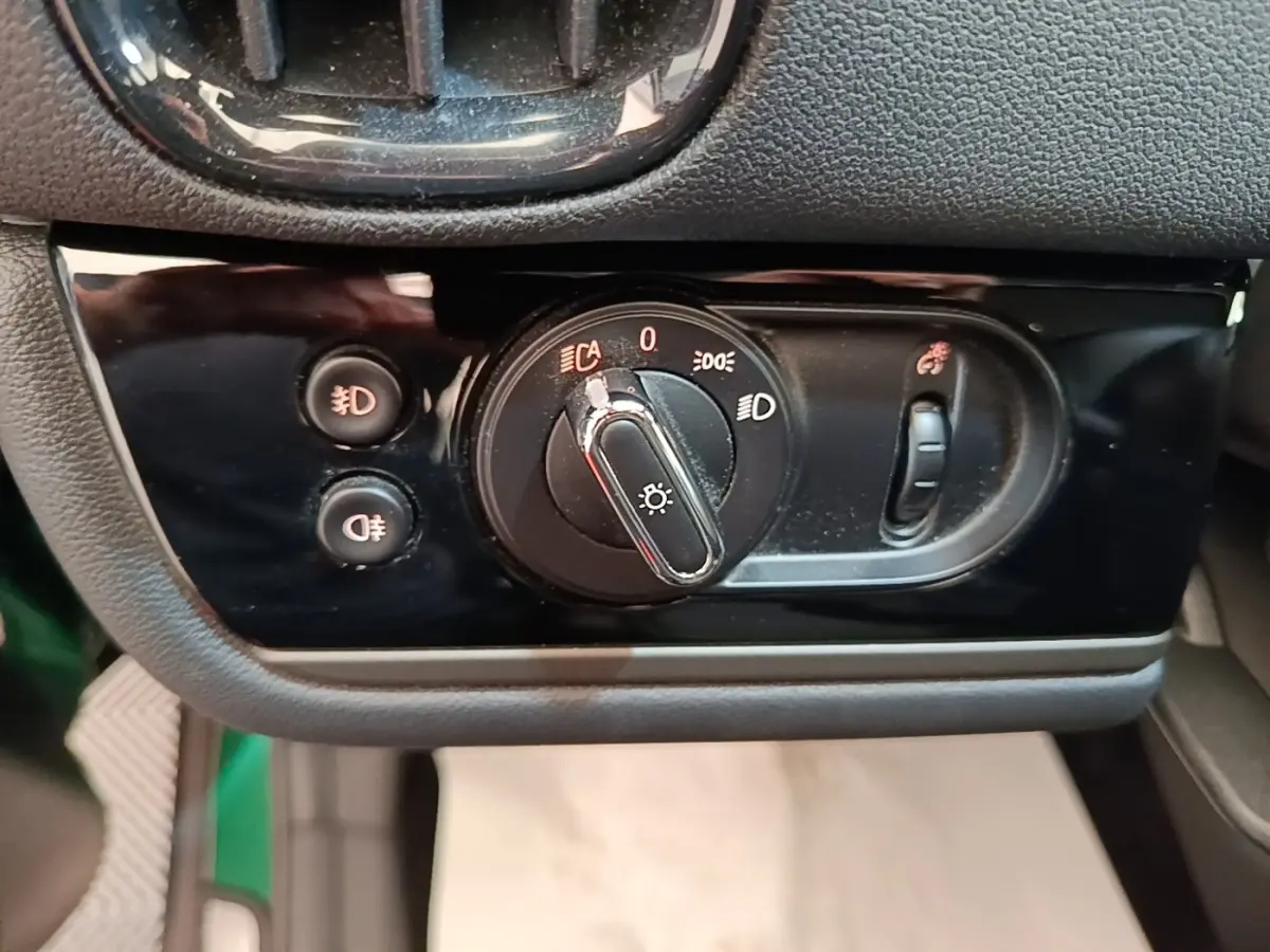 Gros plan sur la commande des phares et antibrouillards du tableau de bord noir d'une MINI Countryman gris clair.