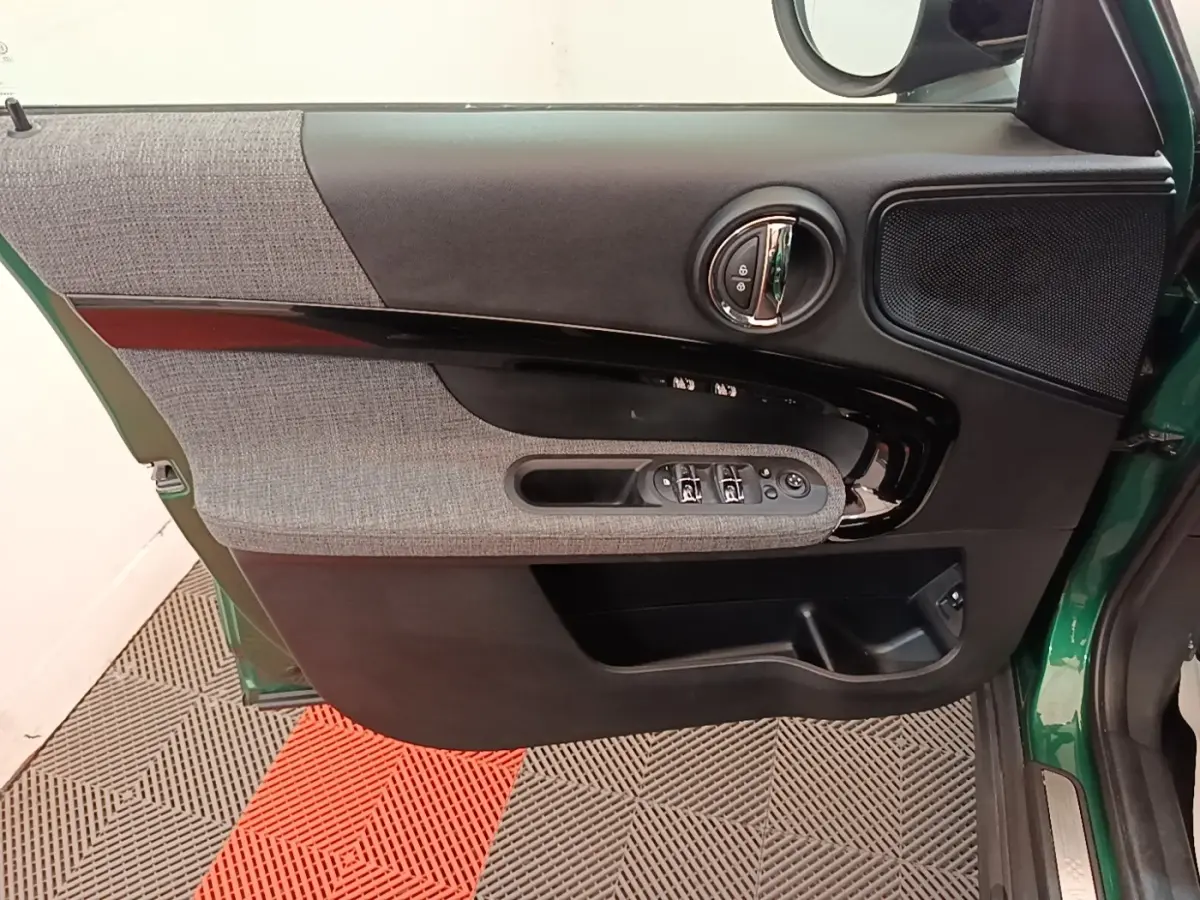 Vue intérieure côté gauche de la porte avant d’un MINI Countryman gris clair avec garniture tissu et commandes électriques.