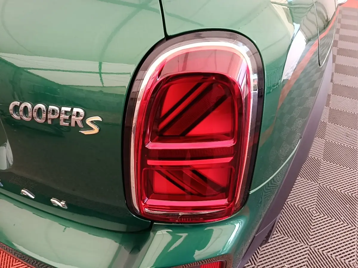 Gros plan sur le feu arrière droit rouge et le logo Cooper S d'une MINI Countryman gris clair, vue arrière partielle.
