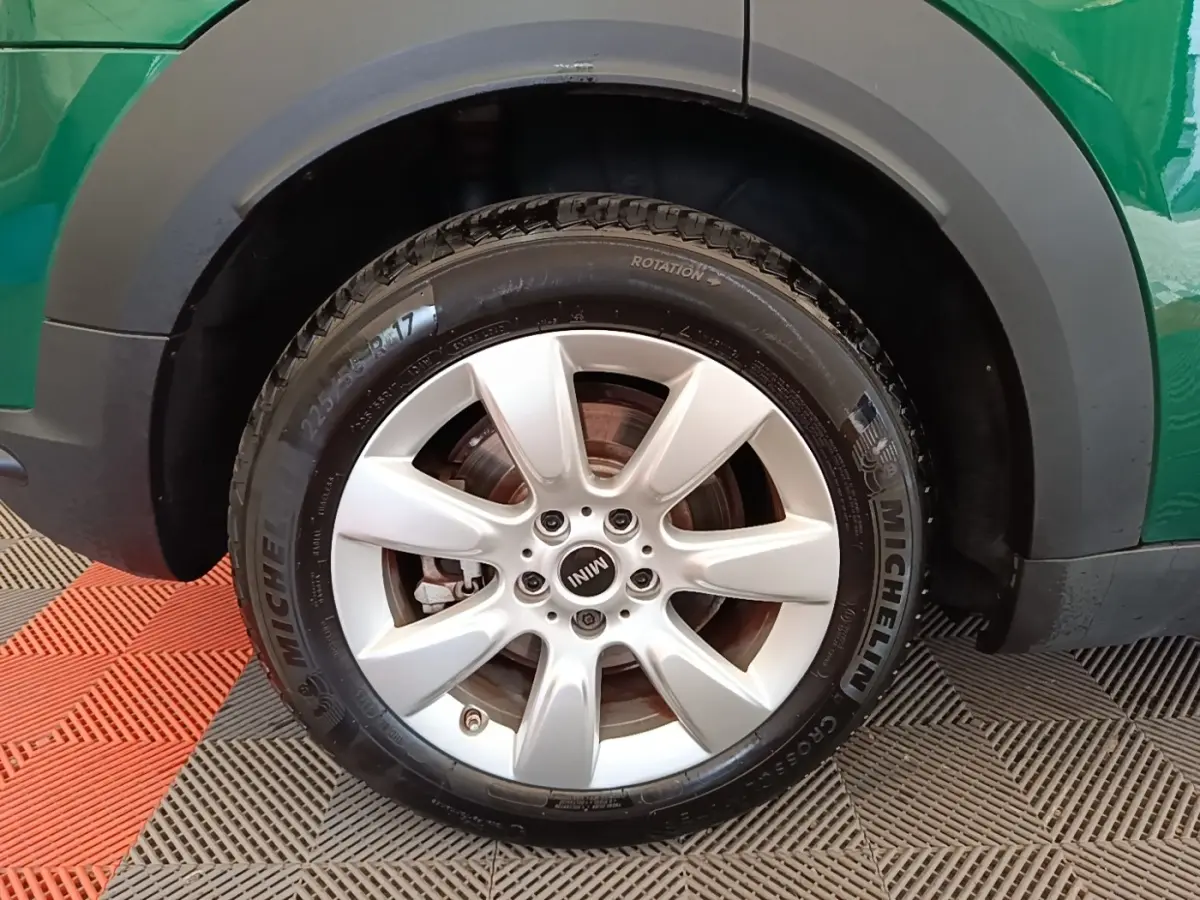 Gros plan sur la roue avant gauche avec jante argentée et pneu Michelin d’un MINI Countryman vert.