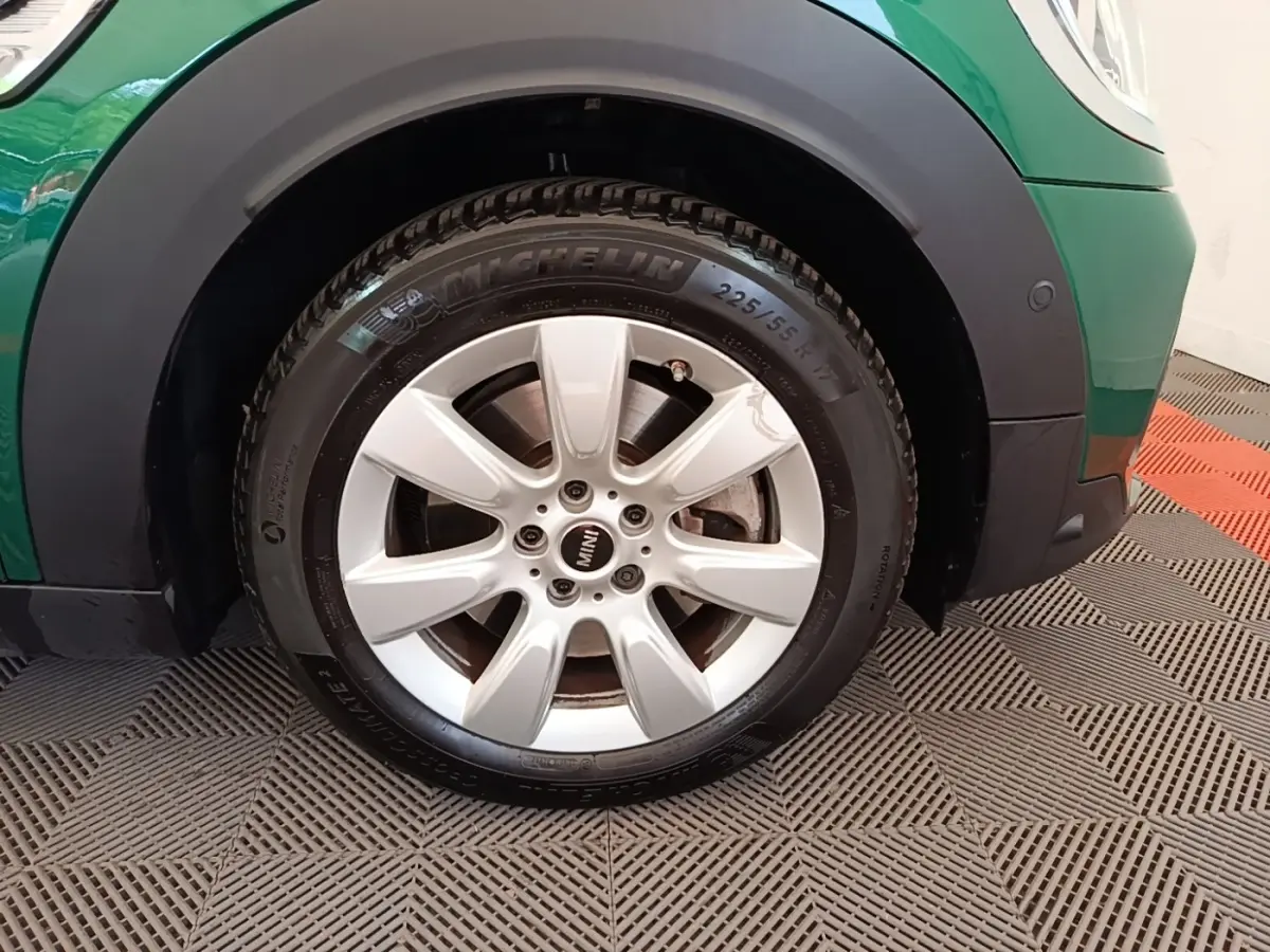 Gros plan sur la roue avant droite argentée d’un MINI Countryman vert avec logo MINI au centre de la jante.