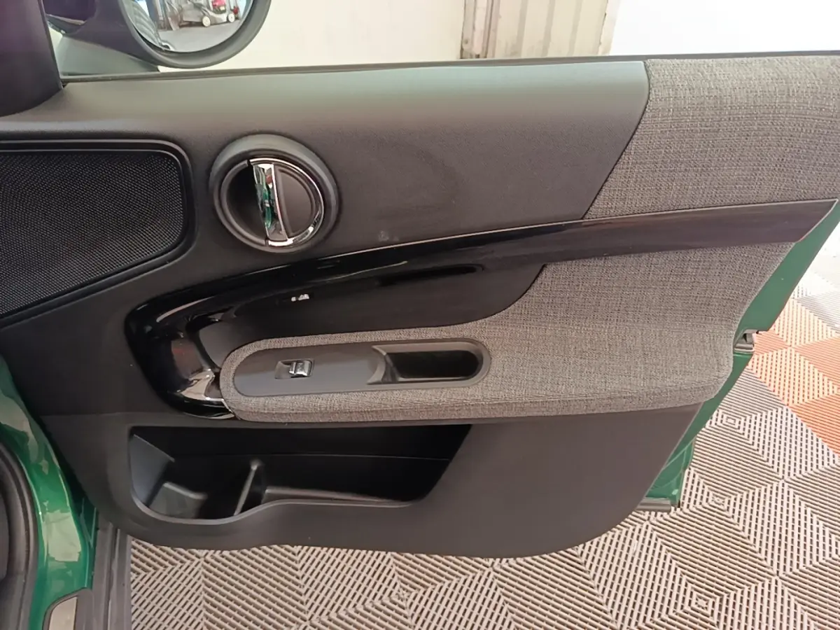 Vue intérieure de la porte avant gauche d'une MINI Countryman 2021, avec garniture tissu gris et plastique noir brillant.