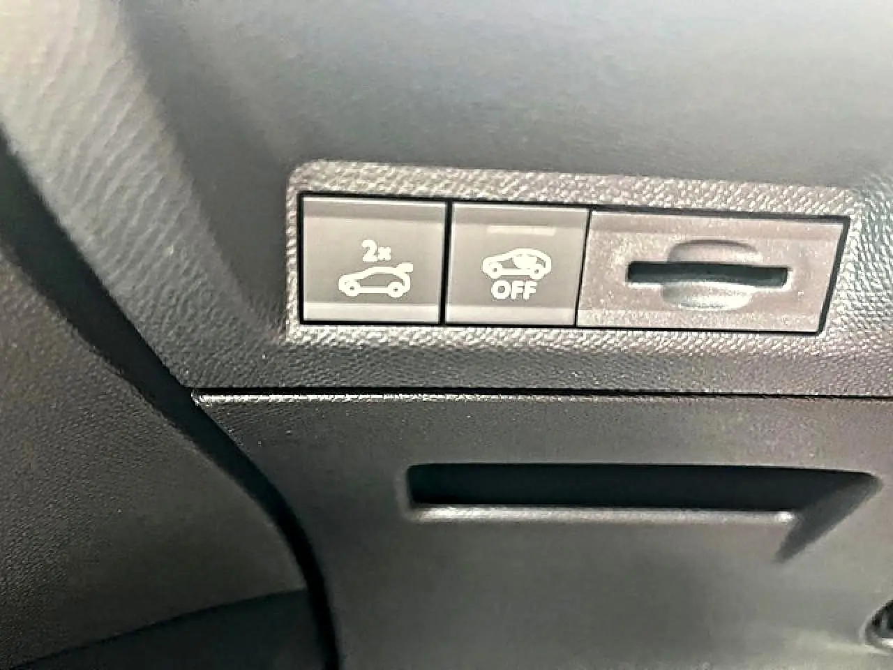 Détail intérieur montrant les boutons d'ouverture du coffre et de désactivation d'assistance sur Peugeot 3008 gris Artense.