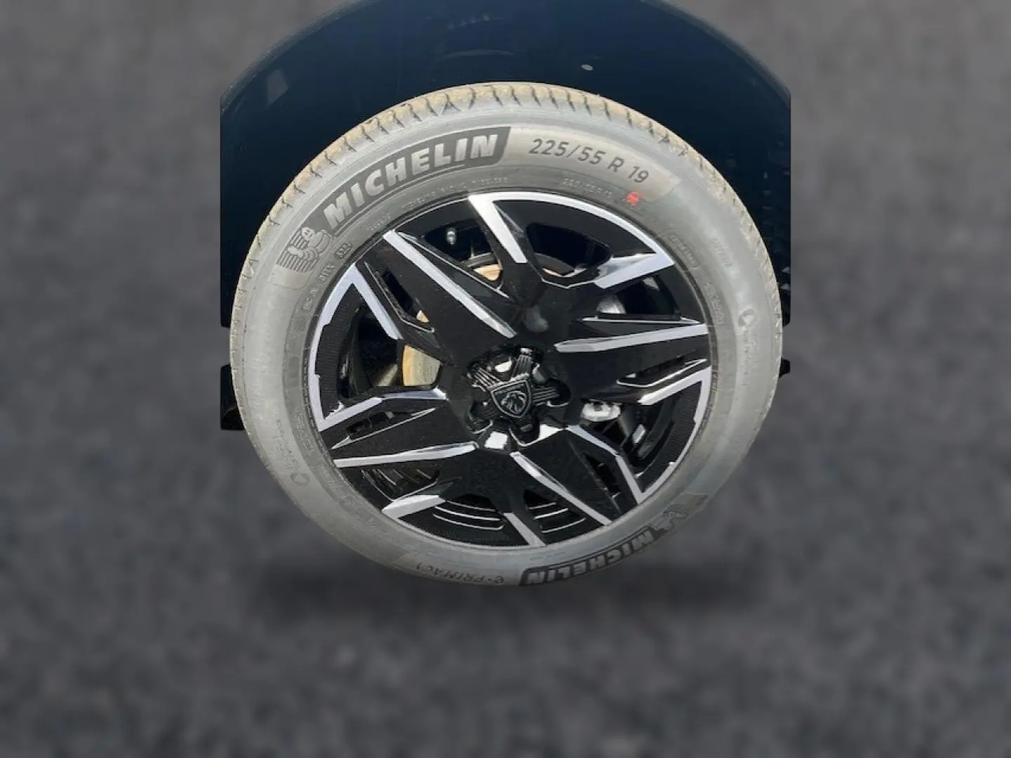 Gros plan sur la jante alu noire et argentée avec logo Peugeot, montée d’un pneu Michelin 225/55 R19.