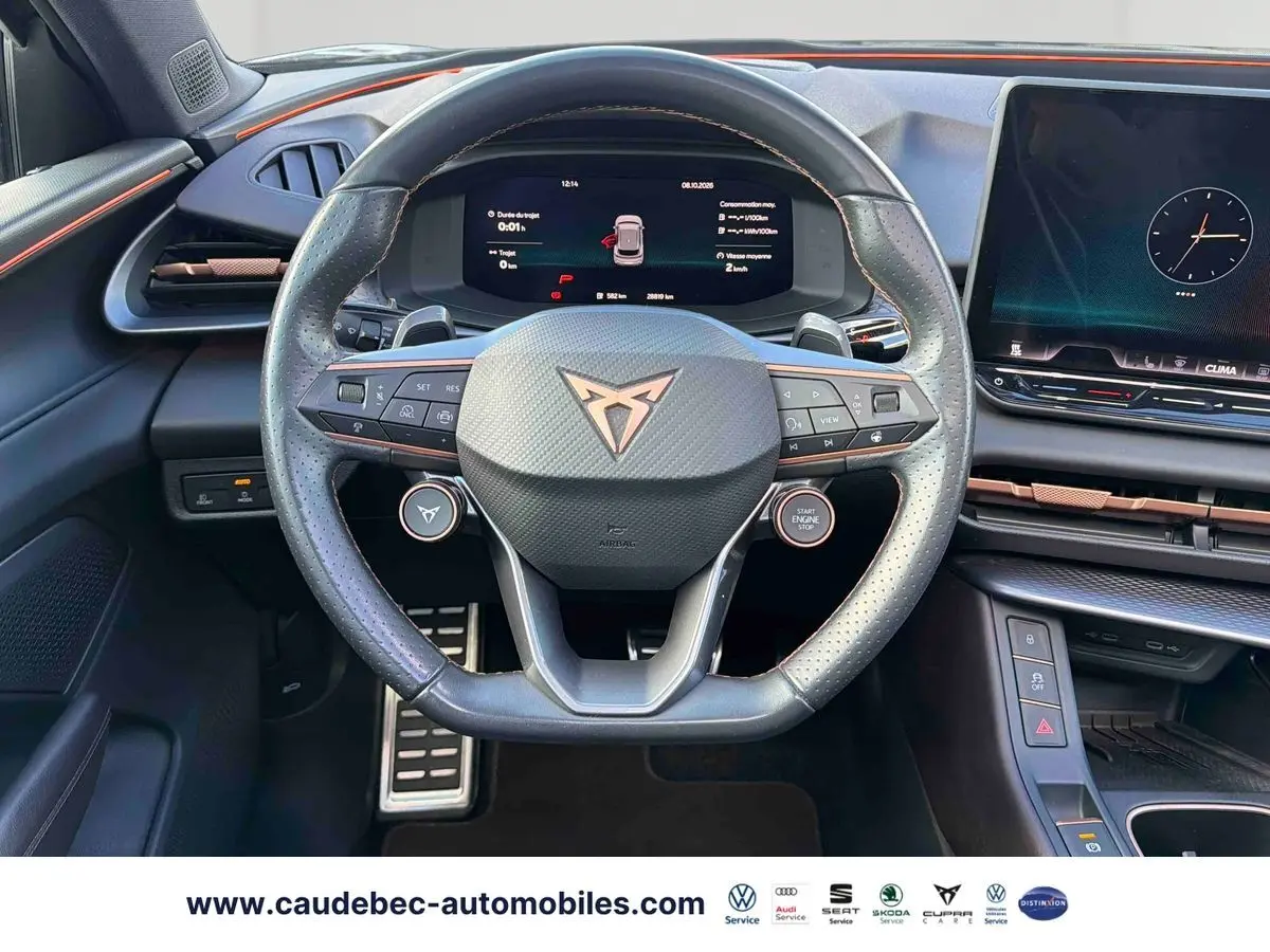 Vue centrée du volant cuir noir avec logo CUPRA cuivré, tableau de bord numérique et planche de bord Bordeaux avec touches cuivrées.