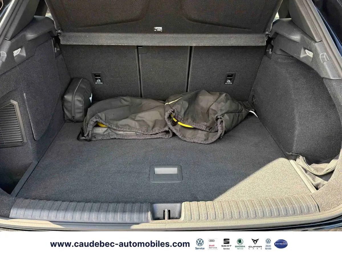 Coffre ouvert de la CUPRA Terramar noire, vue de l'arrière montrant un espace de chargement propre avec housses noires posées.