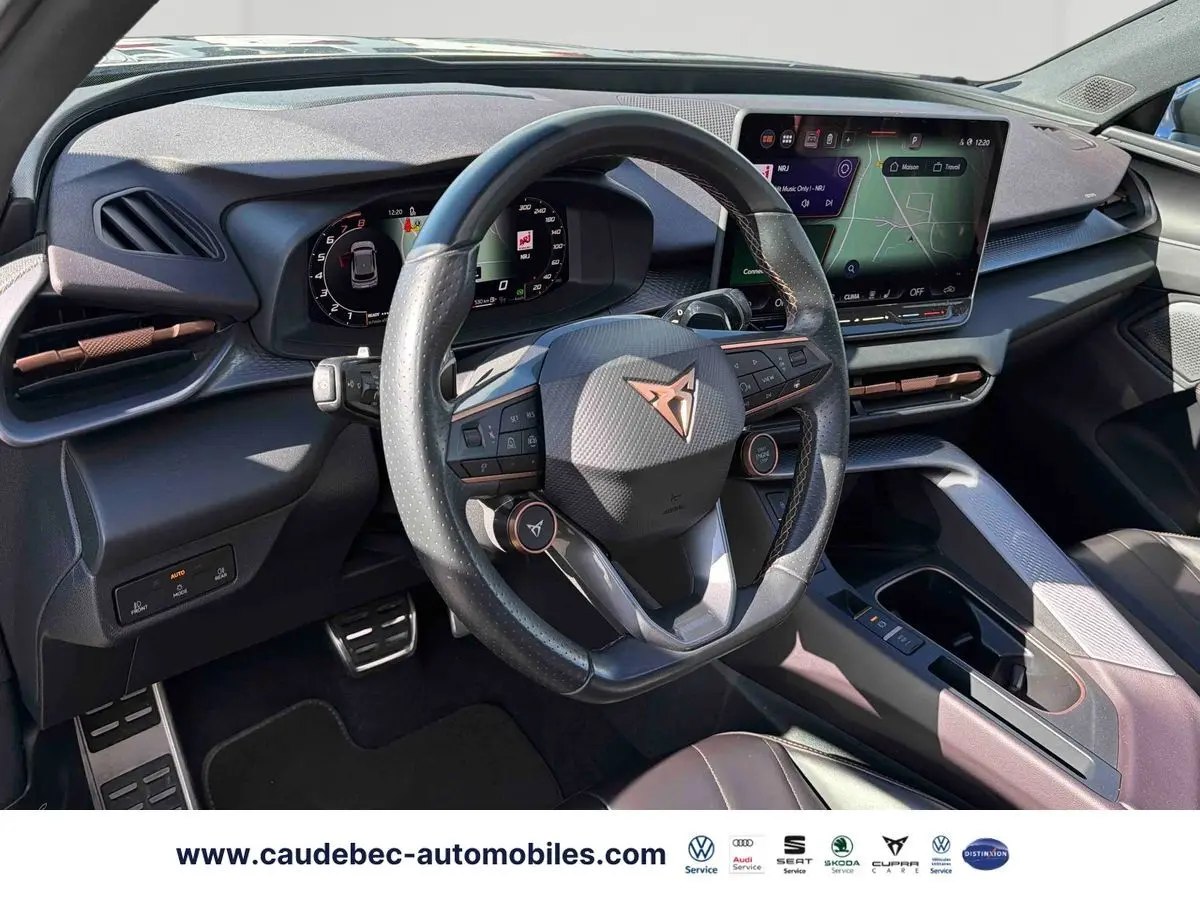 Vue intérieure du poste de conduite du CUPRA Terramar 2024, volant cuir noir avec logo cuivré et tableau de bord digital.