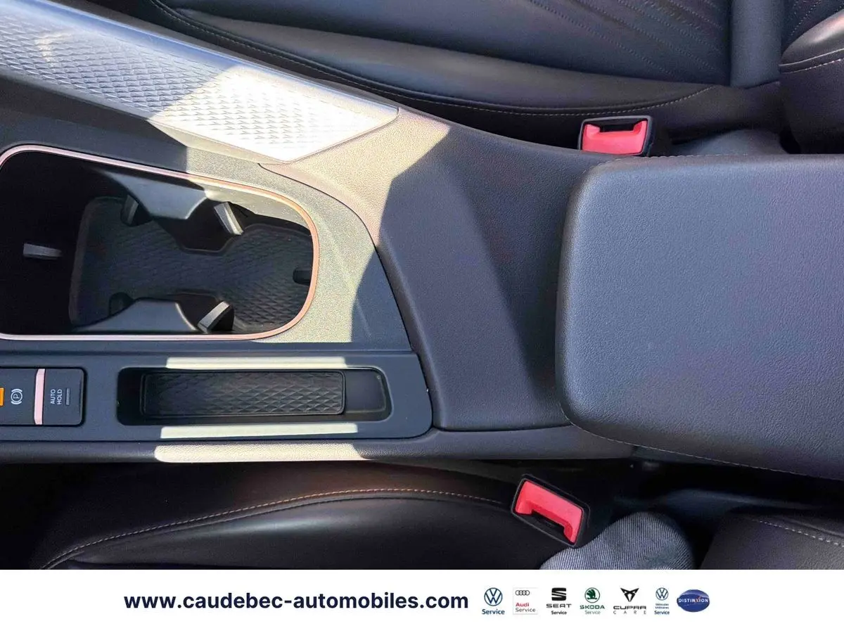 Vue rapprochée de la console centrale noire avec accoudoir et porte-gobelets du CUPRA Terramar 2024.