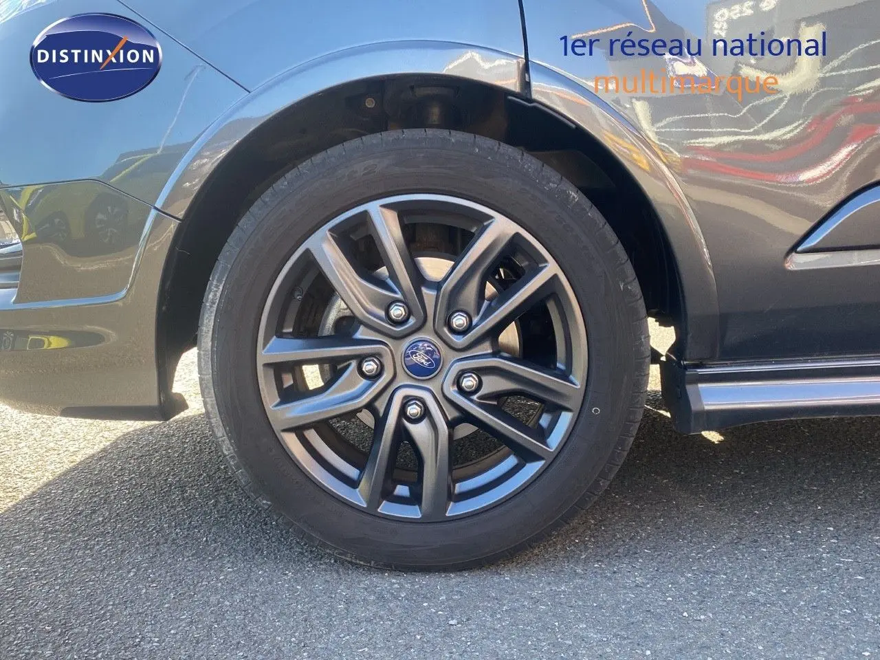 Gros plan sur la roue avant gauche du Ford Transit Custom gris magnetic, mettant en valeur la jante alu sport.