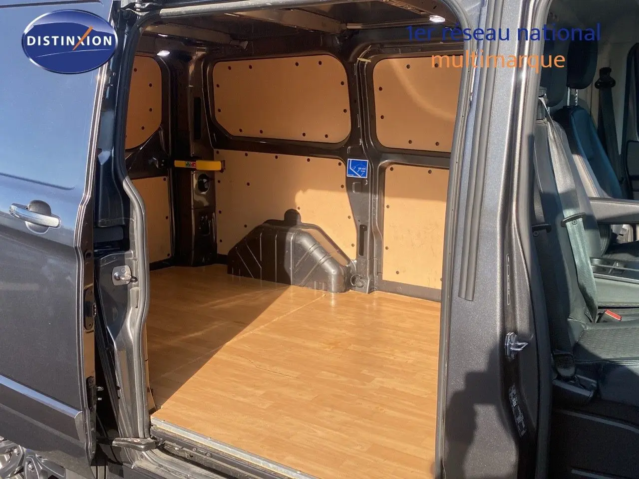 Vue latérale du fourgon Ford Transit Custom gris magnetic 2023, porte coulissante ouverte montrant l'espace de chargement boisé.