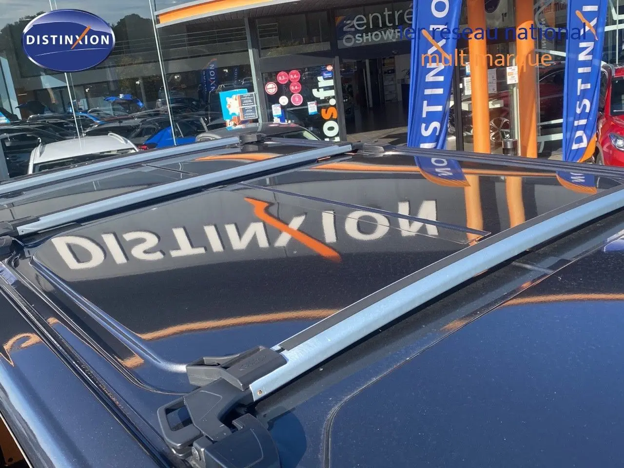 Vue rapprochée du toit gris magnetic du Ford Transit Custom avec barres de toit et reflet du logo Distinxion.