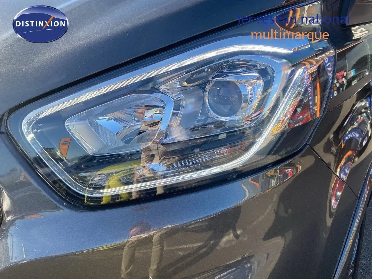 Gros plan sur le phare avant droit du Ford Transit Custom gris magnetic, soulignant ses lignes modernes et précises.