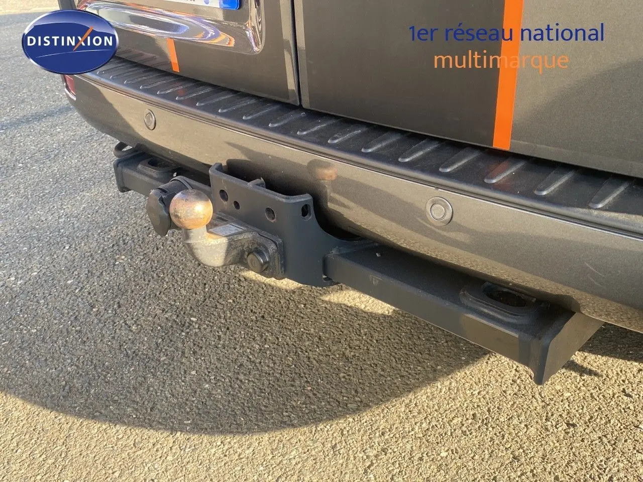 Gros plan sur l'attelage arrière d'un Ford Transit Custom gris magnetic avec capteurs de stationnement intégrés.