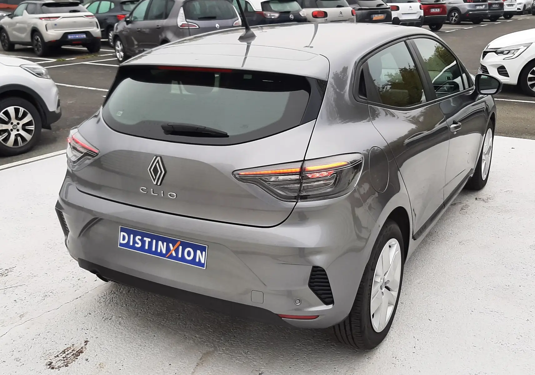 Vue 3/4 arrière droite d'une Renault Clio V E-Tech Full Hybrid 145 Evolution gris schiste avec feux arrière LED allumés.