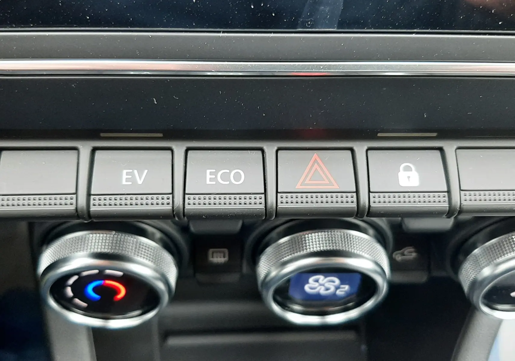 Gros plan sur les commandes centrales du tableau de bord de la Renault Clio V gris schiste, avec boutons EV, ECO et signal d'alerte.