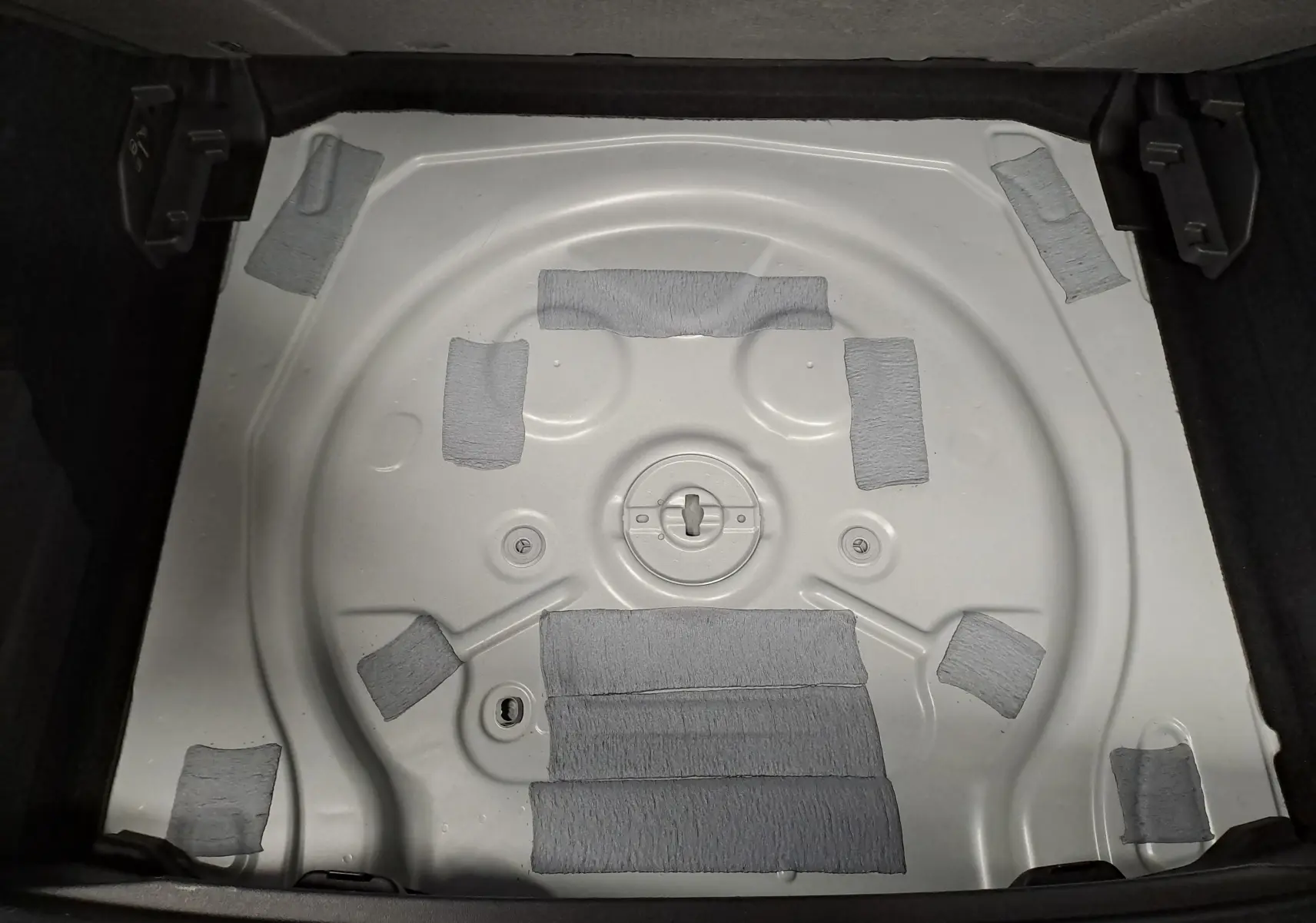 Vue plongeante sur le coffre ouvert d'une CUPRA TERRAMAR blanc Nevada, montrant le logement de roue de secours vide.