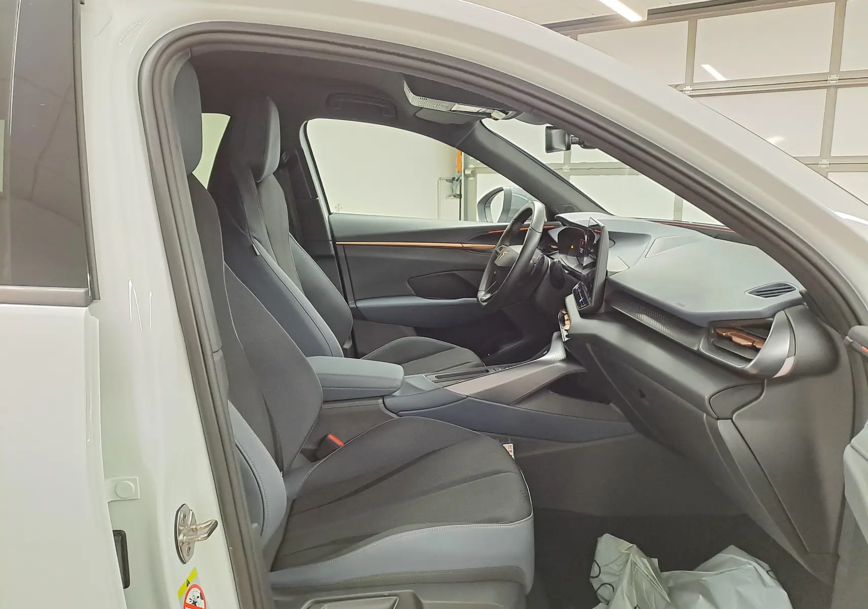 Vue intérieure côté conducteur du CUPRA TERRAMAR blanc Nevada 2025, sièges tissu noir et tableau de bord moderne.