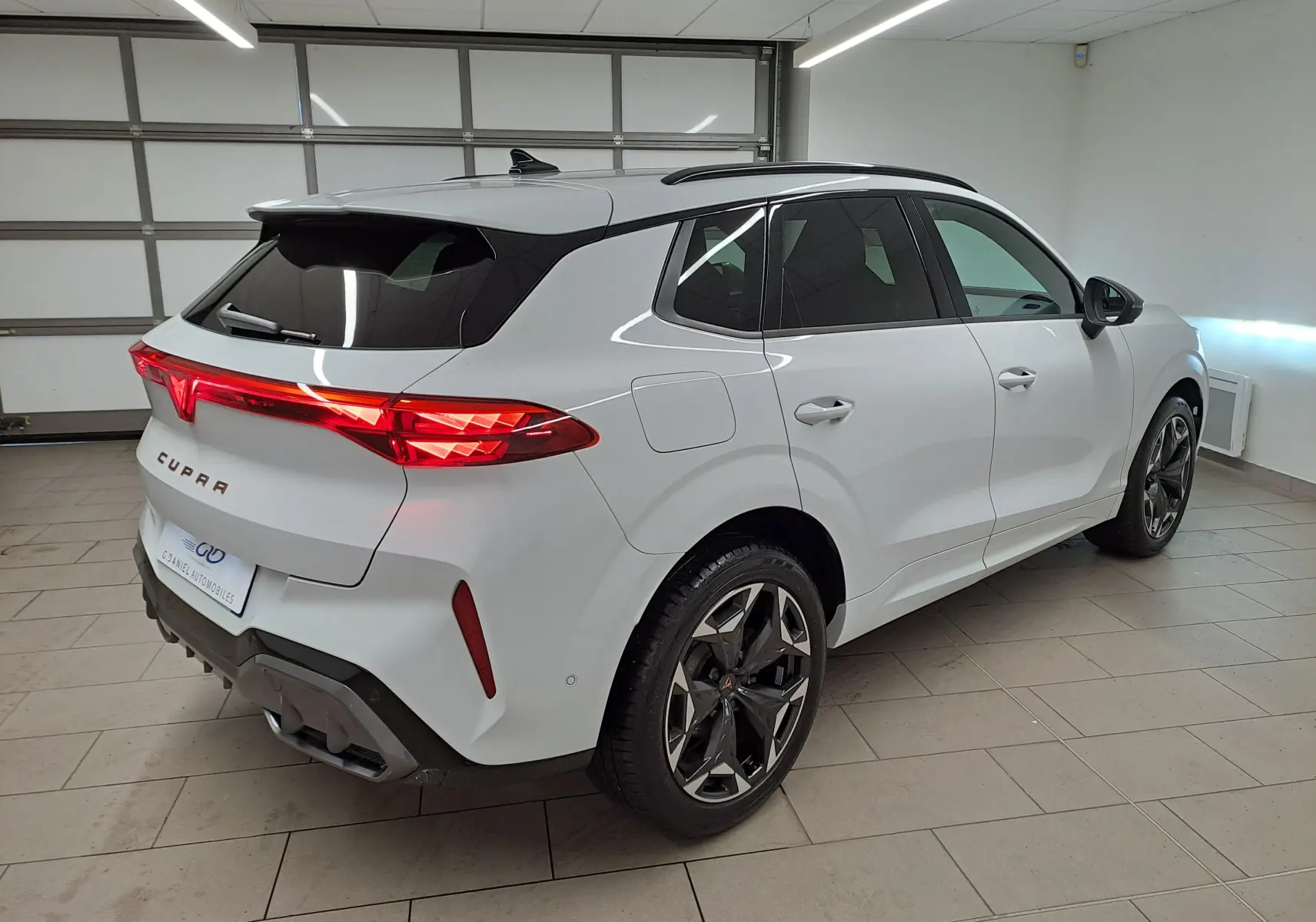 Vue 3/4 arrière droite d'une CUPRA TERRAMAR blanche Nevada avec jantes 19'' Cosmic usinées dans un garage.