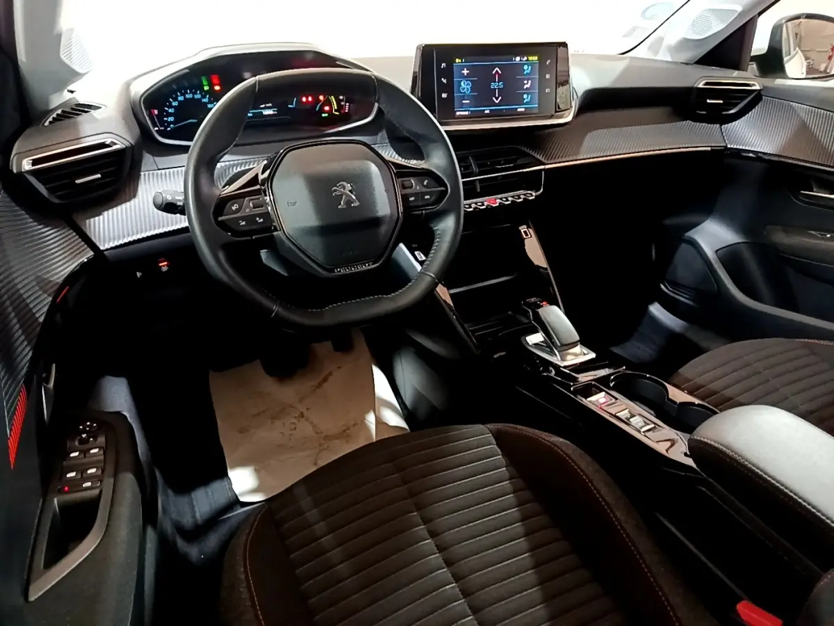 Vue intérieure avant de la Peugeot 208 électrique Active Business, tableau de bord avec écran tactile central et volant cuir multifonctions.