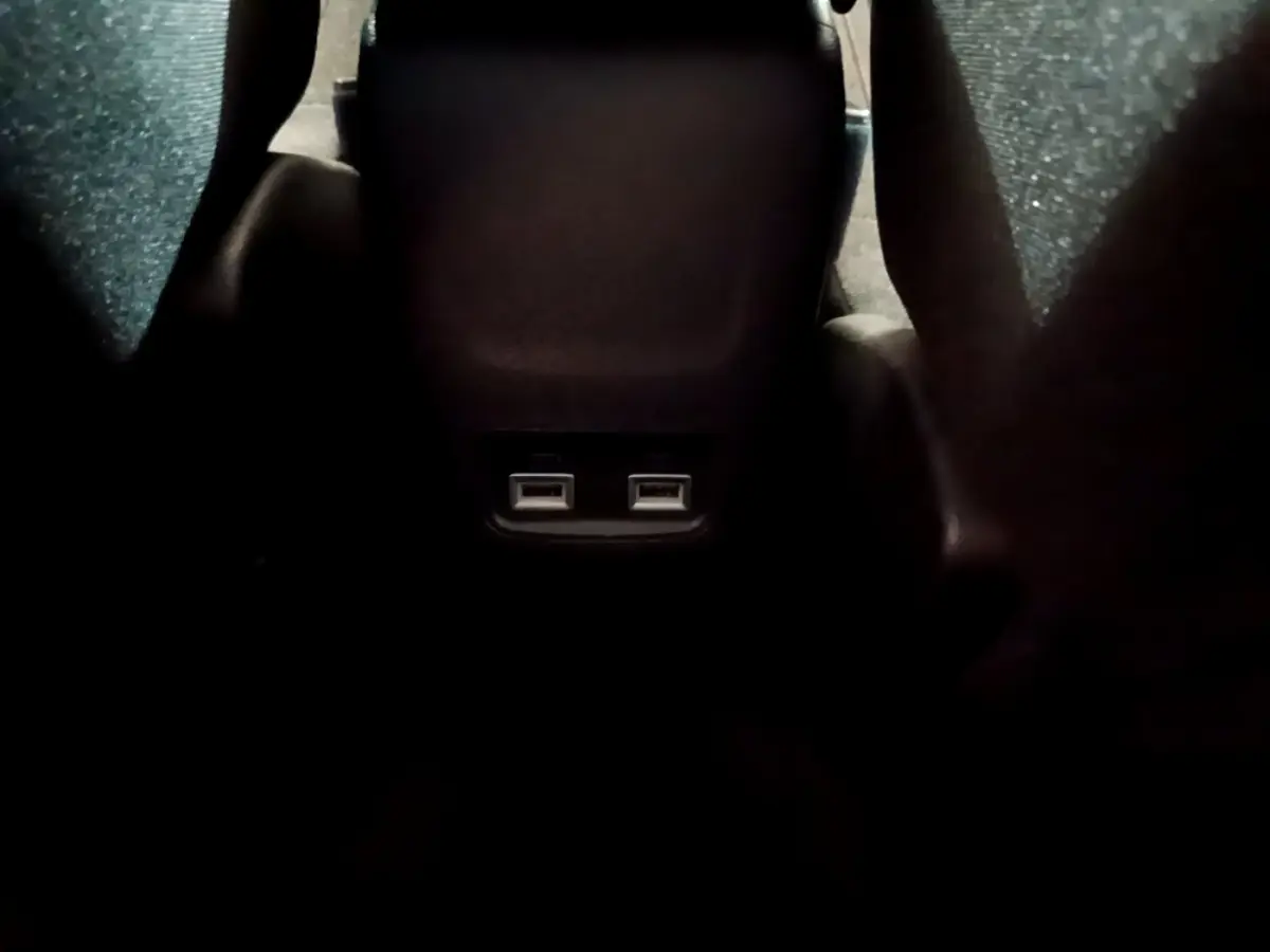 Vue rapprochée des ports USB arrière entre les sièges noirs du Peugeot 208 Electrique Active Business blanc.