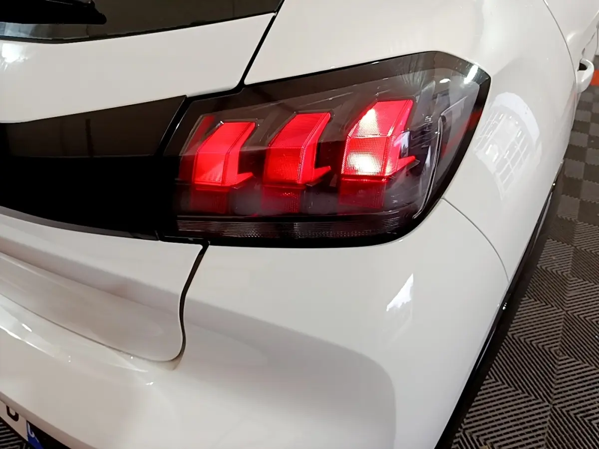 Gros plan sur le feu arrière droit rouge d'une Peugeot 208 électrique Active Business blanche, vue arrière côté droit.