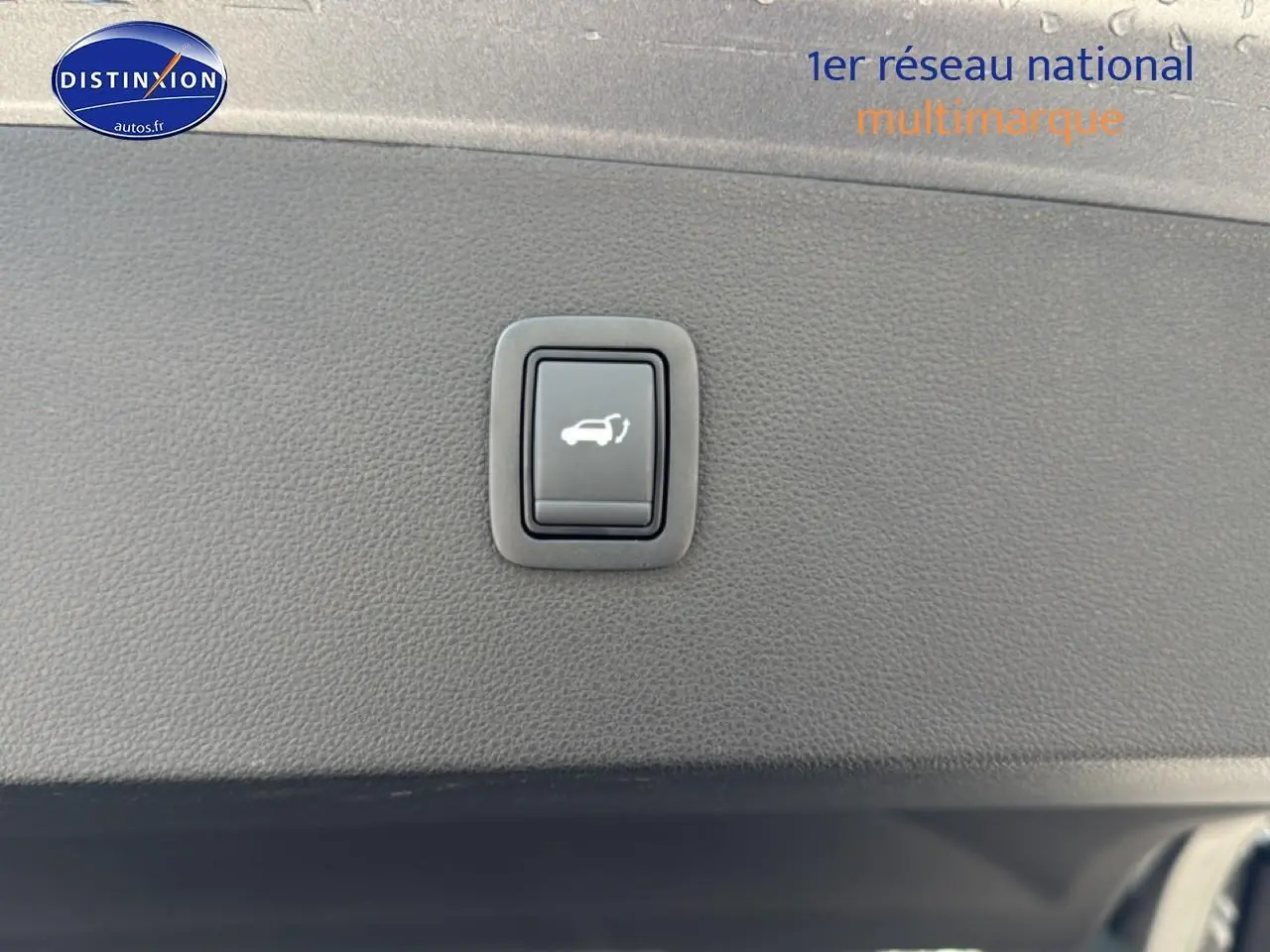 Bouton d'ouverture du hayon sur la garniture intérieure noire du coffre du Dacia Bigster gris schiste.