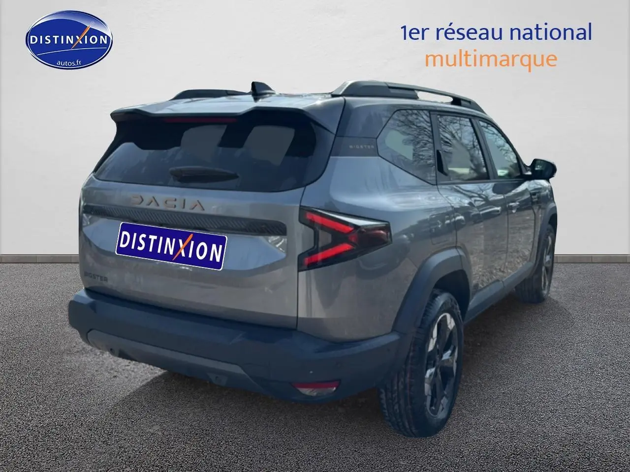 SUV Dacia Bigster gris schiste vu en 3/4 arrière droit avec feux arrière LED et barres de toit visibles.