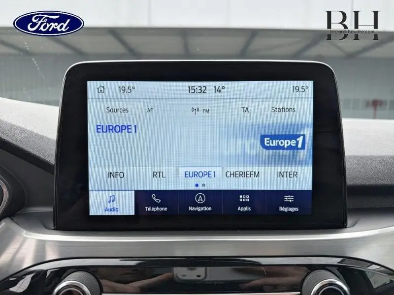 Écran tactile central du Ford Kuga 2023 affichant la radio Europe 1, avec tableau de bord gris et noir.