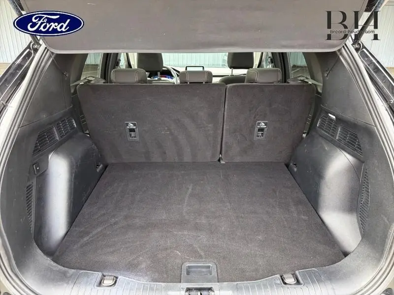 Vue intérieure du coffre spacieux du Ford Kuga 2023 noir Agate avec banquette arrière en position verticale.