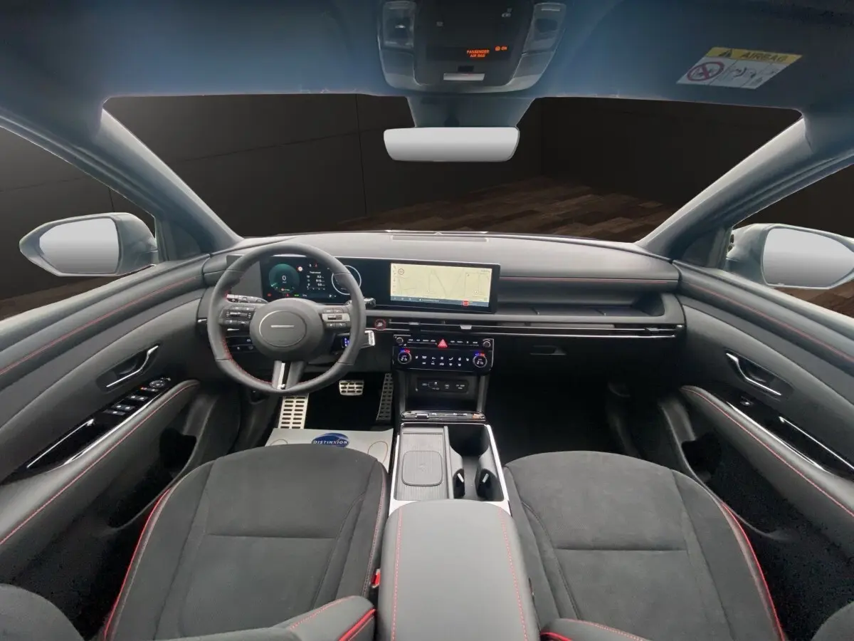 Vue intérieure avant du Hyundai Tucson 1.6 Hybrid gris foncé, avec tableau de bord numérique et écran tactile central.