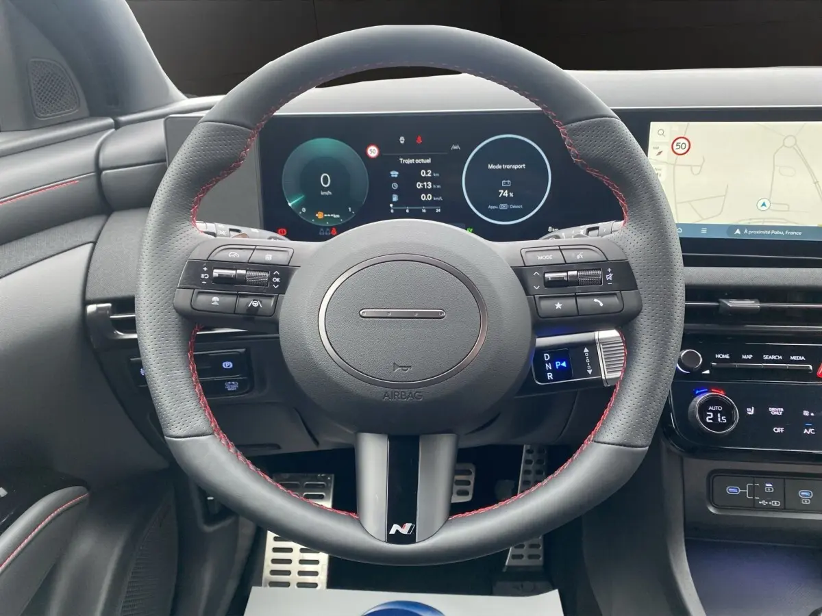 Vue intérieure centrée sur le volant cuir noir avec surpiqûres rouges du Hyundai Tucson 1.6 Hybrid N Line 2026.