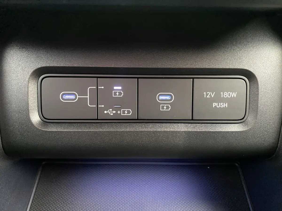 Gros plan sur les ports USB-C et prise 12V avec éclairage bleu dans l’habitacle du Hyundai Tucson gris foncé.