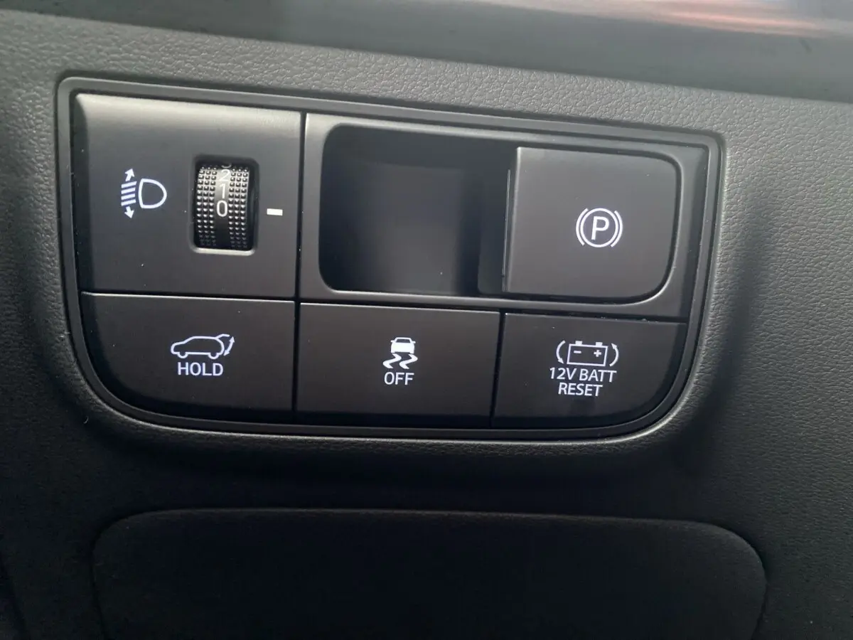 Gros plan sur les commandes noires du tableau de bord du Hyundai Tucson 1.6 Hybrid N Line, avec boutons éclairés blancs.