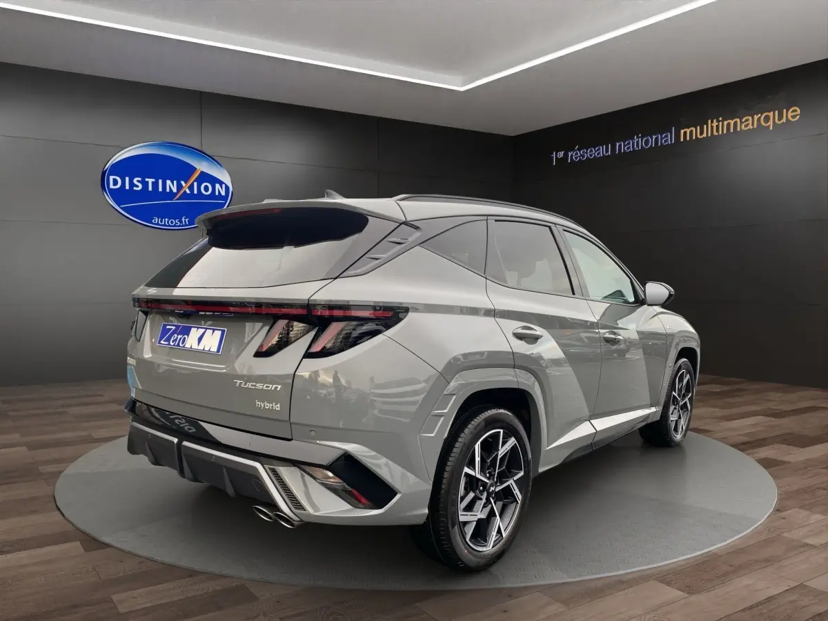Vue 3/4 arrière droite du Hyundai Tucson 1.6 Hybrid gris foncé avec feux arrière LED et jantes alliage distinctives.