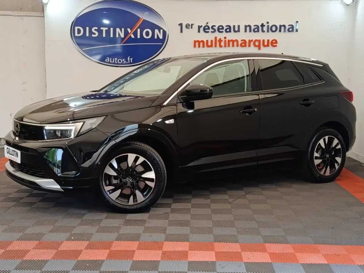 Opel Grandland hybride rechargeable noir en profil droit, avec jantes bicolores et calandre moderne en showroom.
