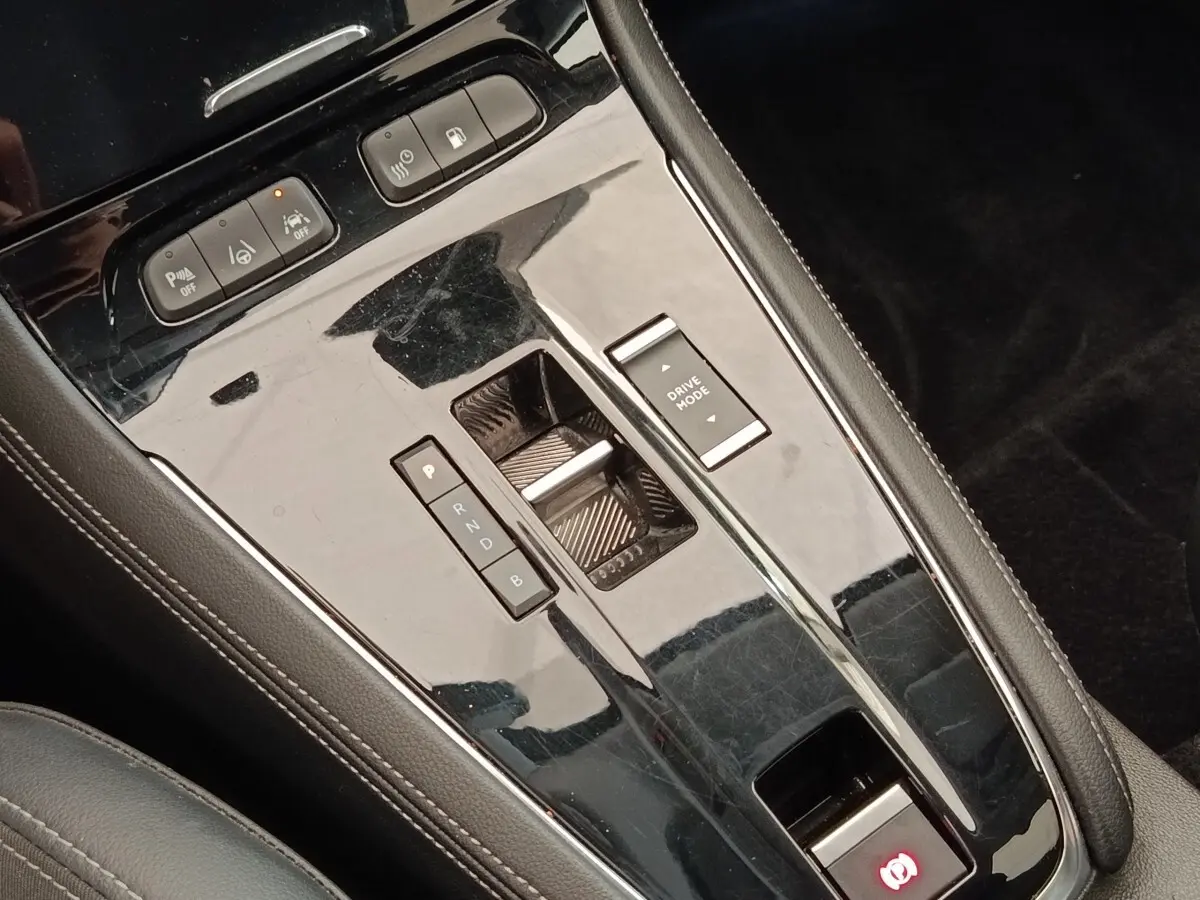 Vue rapprochée de la console centrale noire brillante de l’Opel Grandland hybride avec commandes de boîte automatique et mode de conduite.